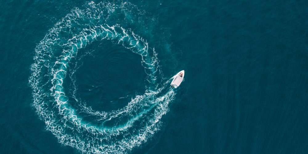 Aerial view of a boat driving in circle in the sea.